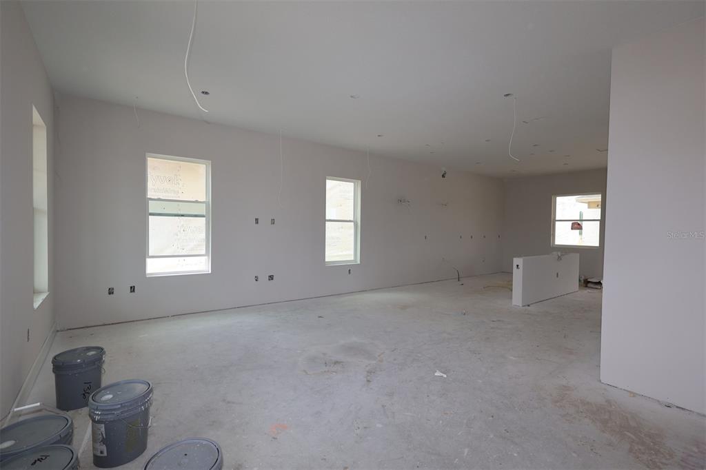 An unfinished room with white walls, concrete floors, several windows, and paint buckets on floor — 6721 RUCKSACK ROAD, ST CLOUD, FL