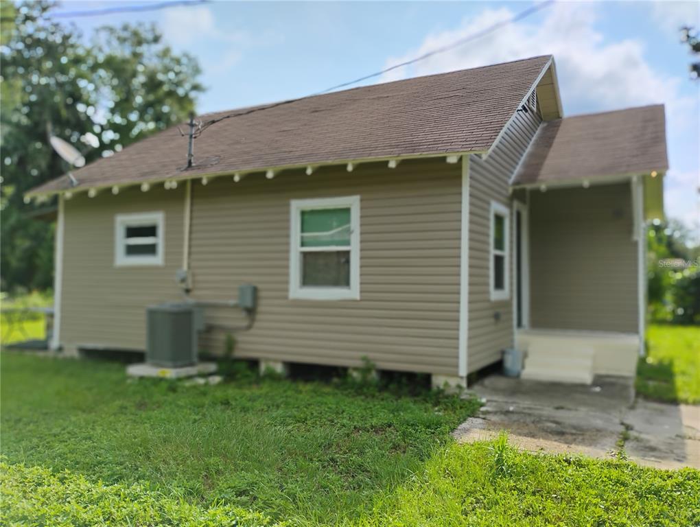 A side view of a small, tan-sided house with a shingled roof and an air conditioner — 765 NE 6TH TERRACE, CRYSTAL RIVER, FL