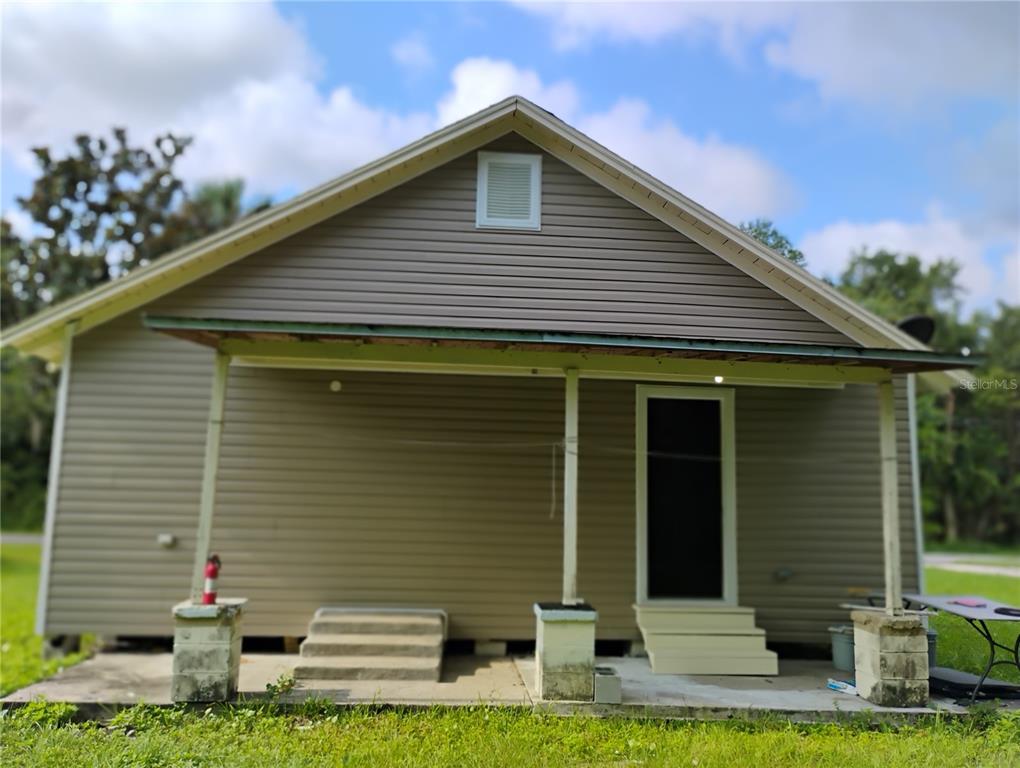 The exterior of a house features beige vinyl siding, a covered porch, and concrete steps — 765 NE 6TH TERRACE, CRYSTAL RIVER, FL