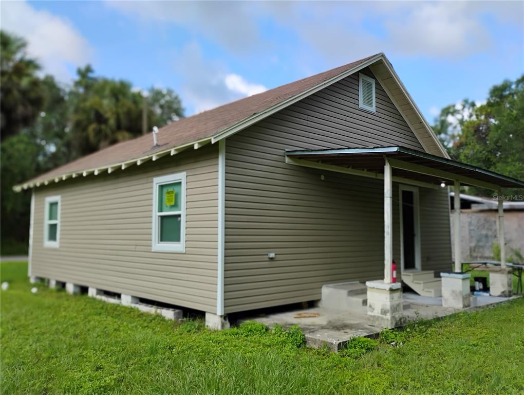 A single-story house with tan vinyl siding, a metal roof, and a small front porch — 765 NE 6TH TERRACE, CRYSTAL RIVER, FL