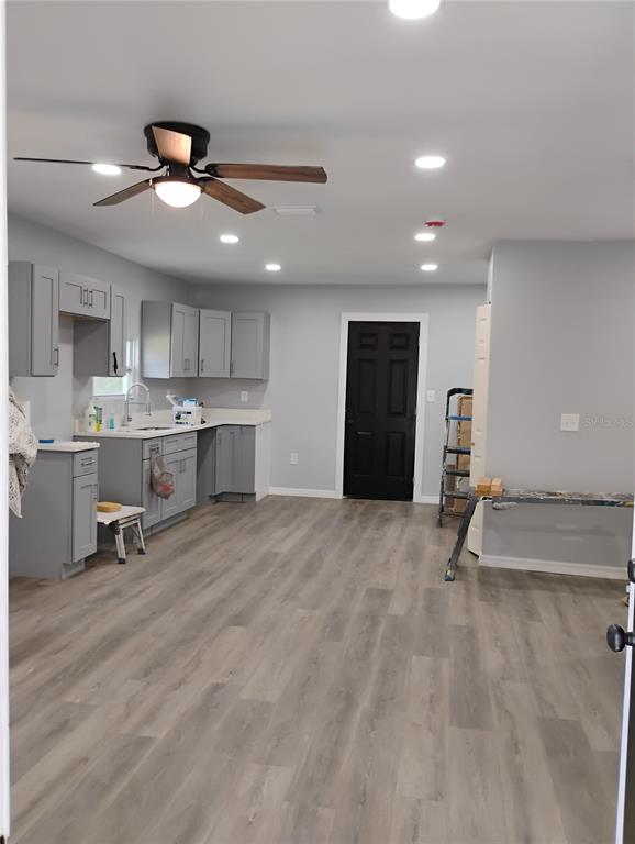 A kitchen with grey cabinets, light wood-look flooring, and a black door — 765 NE 6TH TERRACE, CRYSTAL RIVER, FL
