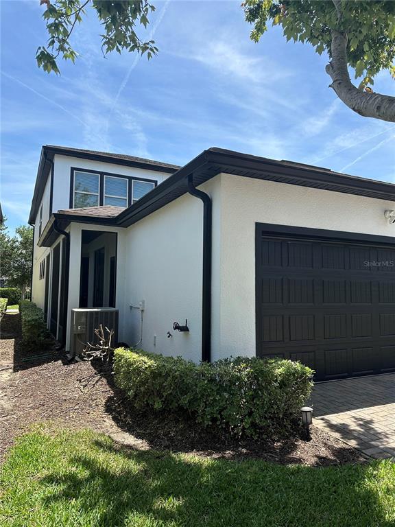 A kitchen features white cabinetry, stainless steel appliances, a granite countertop, and three bar stools — 7190 ENCHANTED LAKE DRIVE, WINTER GARDEN, FL