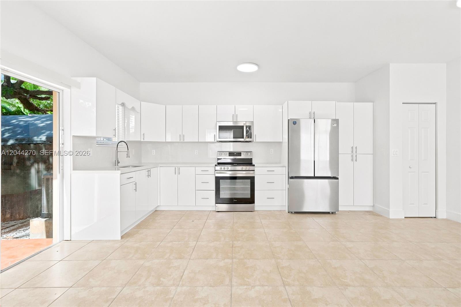 A kitchen features white cabinetry, stainless steel appliances, and light-colored tile flooring — 145 NE 60th St # 145, Miami FL 33137, MIAMI, FL