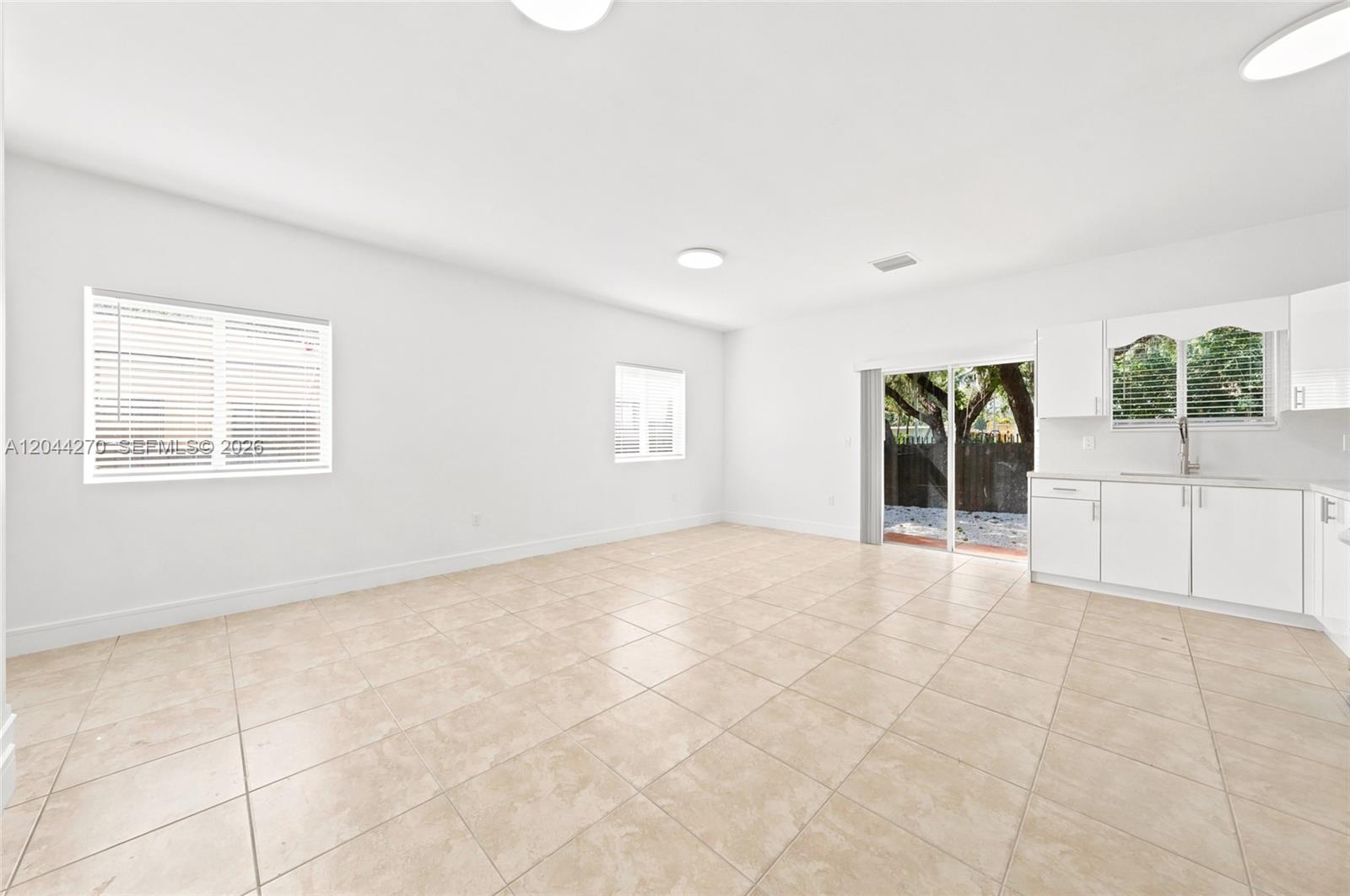 A bright, open-concept room features white walls, tile flooring, a kitchenette, and sliding glass doors — 145 NE 60th St # 145, Miami FL 33137, MIAMI, FL