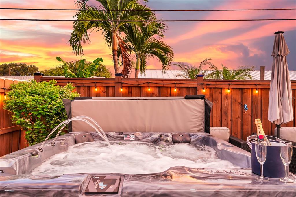 A hot tub with a fountain feature sits on a patio against a wooden fence — 363 HARBOR DR, CAPE CANAVERAL, FL