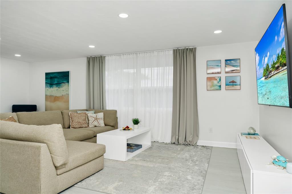 A living room features a beige sectional sofa, a white coffee table, and a wall-mounted television — 363 HARBOR DR, CAPE CANAVERAL, FL