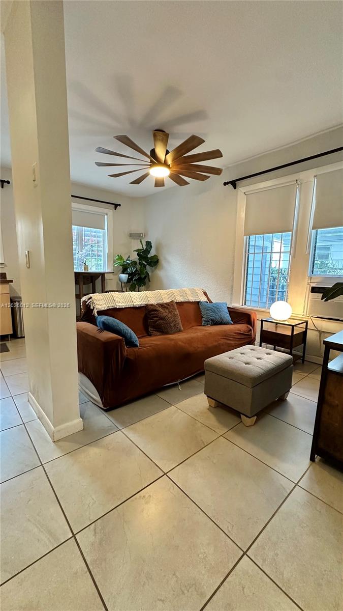 A living room features a brown sofa, a gray ottoman, and a ceiling fan — 842 Meridian Ave # 1E, Miami Beach FL 33139, MIAMI BEACH, FL