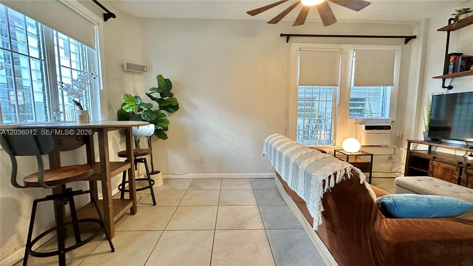 A living room features tiled floors, a ceiling fan, a sofa, and a dining area — 842 Meridian Ave # 1E, Miami Beach FL 33139, MIAMI BEACH, FL