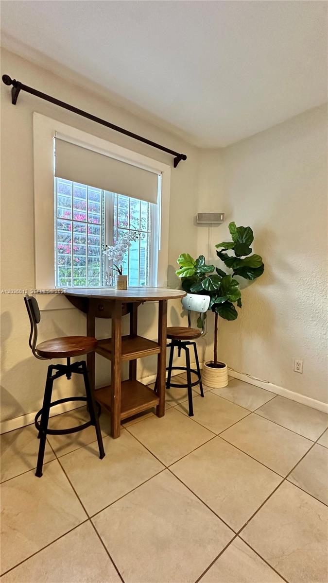 A small dining area features a round wooden table, two stools, and a potted plant — 842 Meridian Ave # 1E, Miami Beach FL 33139, MIAMI BEACH, FL