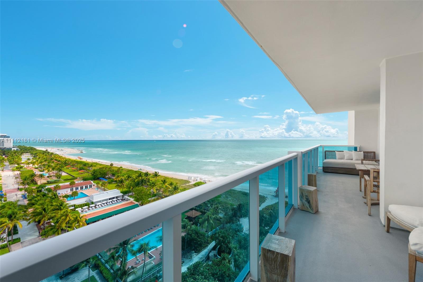 A high-rise balcony overlooks a beach, ocean, and coastal resort area with swimming pools — 102 24th St # 1219, Miami Beach FL 33139, MIAMI BEACH, FL