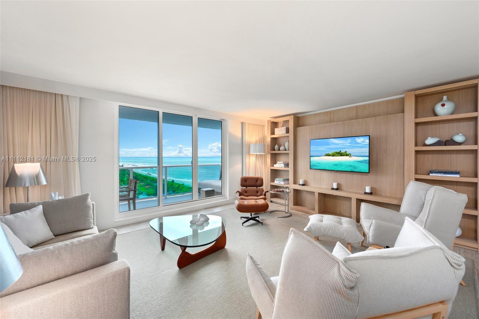 A living room features light wood built-in shelving, a glass coffee table, and ocean views — 102 24th St # 1219, Miami Beach FL 33139, MIAMI BEACH, FL