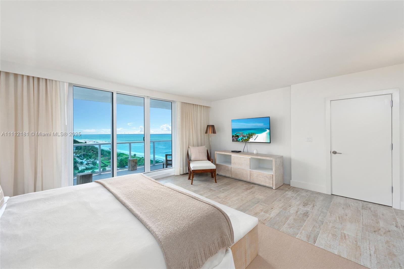 A bedroom features a bed, a television, a chair, and a balcony overlooking the ocean — 102 24th St # 1219, Miami Beach FL 33139, MIAMI BEACH, FL