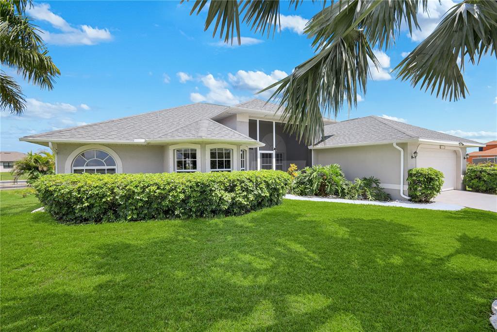 A single-story house with a gray shingled roof, beige stucco walls, and a manicured lawn — 1431 NW 3RD PLACE, CAPE CORAL, FL