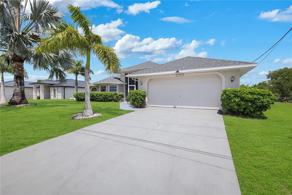 A single-story house with a concrete driveway, a two-car garage, and palm trees — 1431 NW 3RD PLACE, CAPE CORAL, FL
