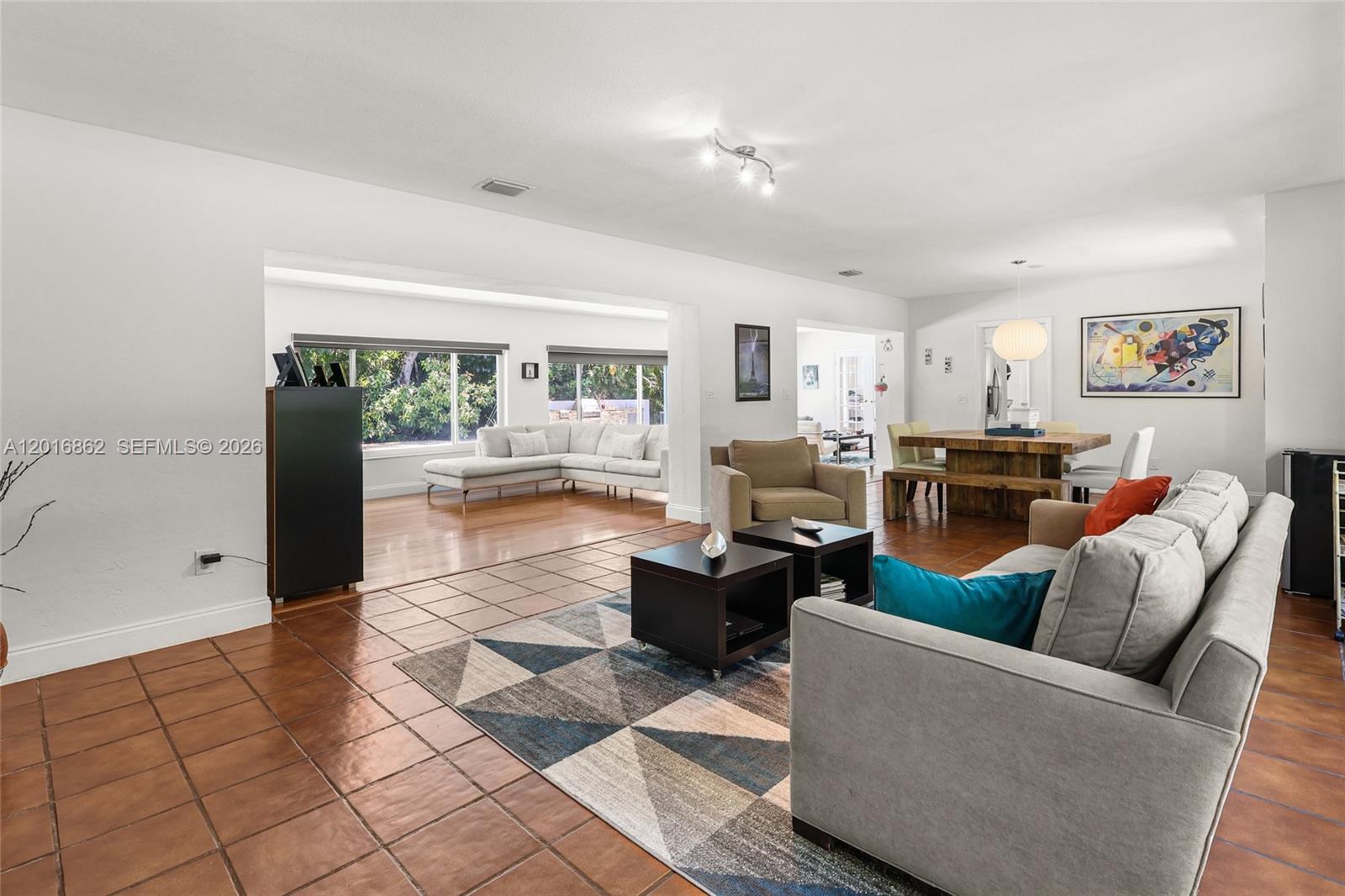 A spacious living and dining area features tile flooring, a geometric rug, and large windows — 7800 SW 132nd St, Pinecrest FL 33156, PINECREST, FL