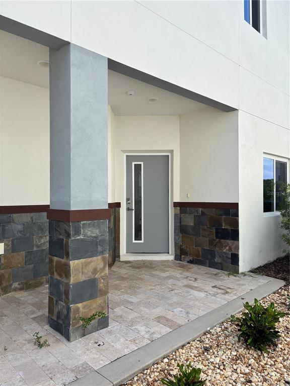 The exterior entrance features a gray door, stone veneer siding, and a paved porch — 2049 GREENBRIAR TERRACE, DAVENPORT, FL