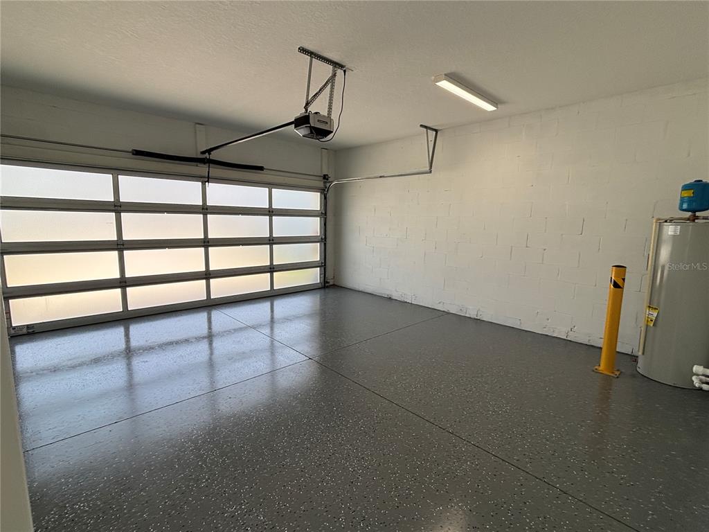 A garage with a multi-pane glass door, painted block walls, and speckled epoxy flooring — 2049 GREENBRIAR TERRACE, DAVENPORT, FL