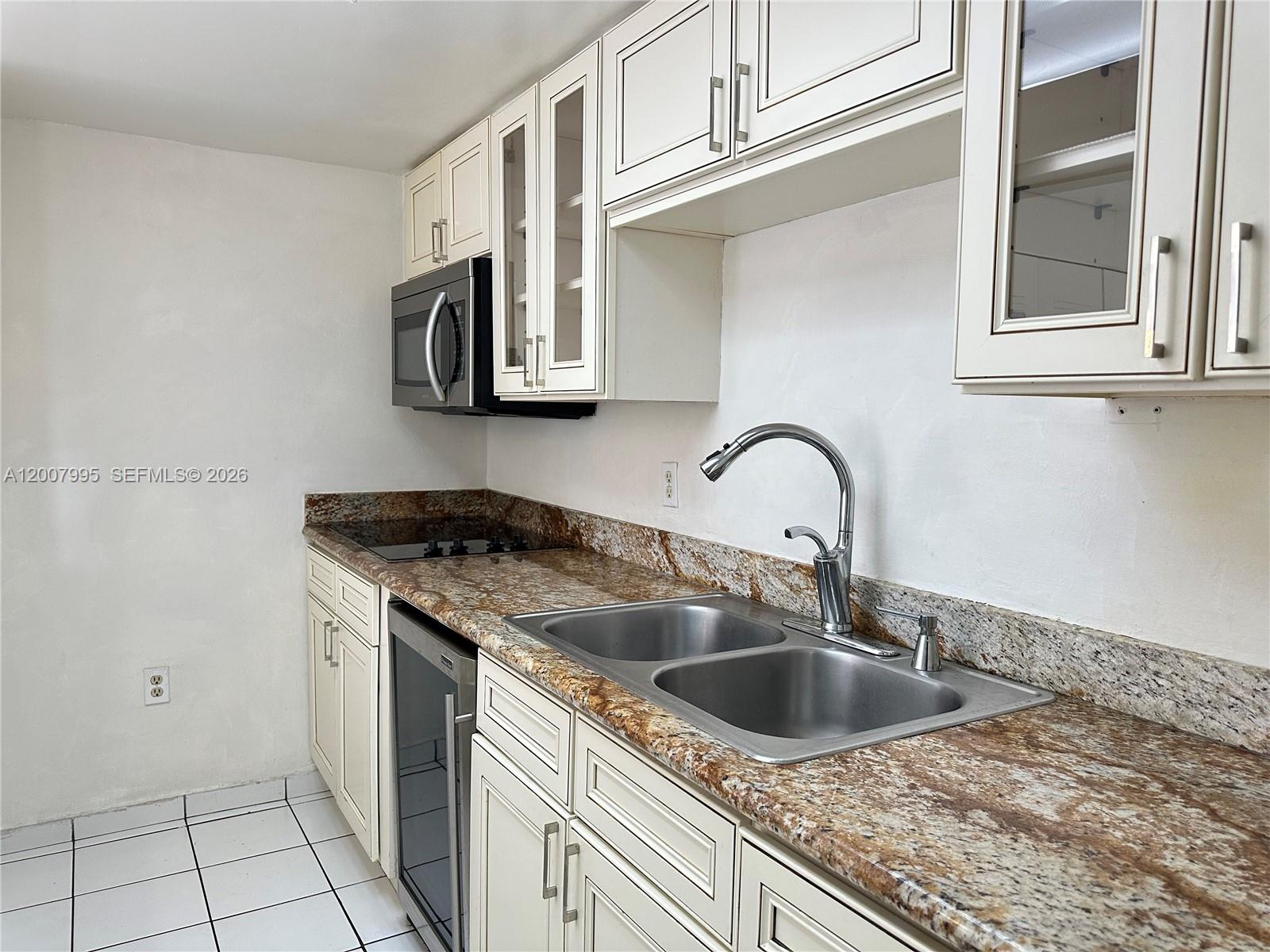 An empty room features white tiled floors, light-colored walls, and a sliding glass balcony door — 802 NW 87th Ave # 315, Miami FL 33172, MIAMI, FL