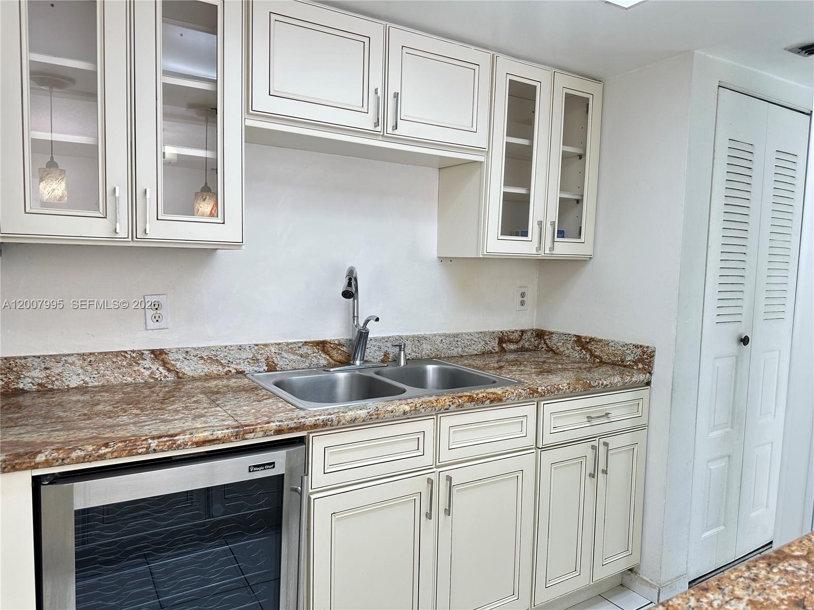 A kitchen features cream-colored cabinets, a granite countertop, a double sink, and a wine cooler — 802 NW 87th Ave # 315, Miami FL 33172, MIAMI, FL