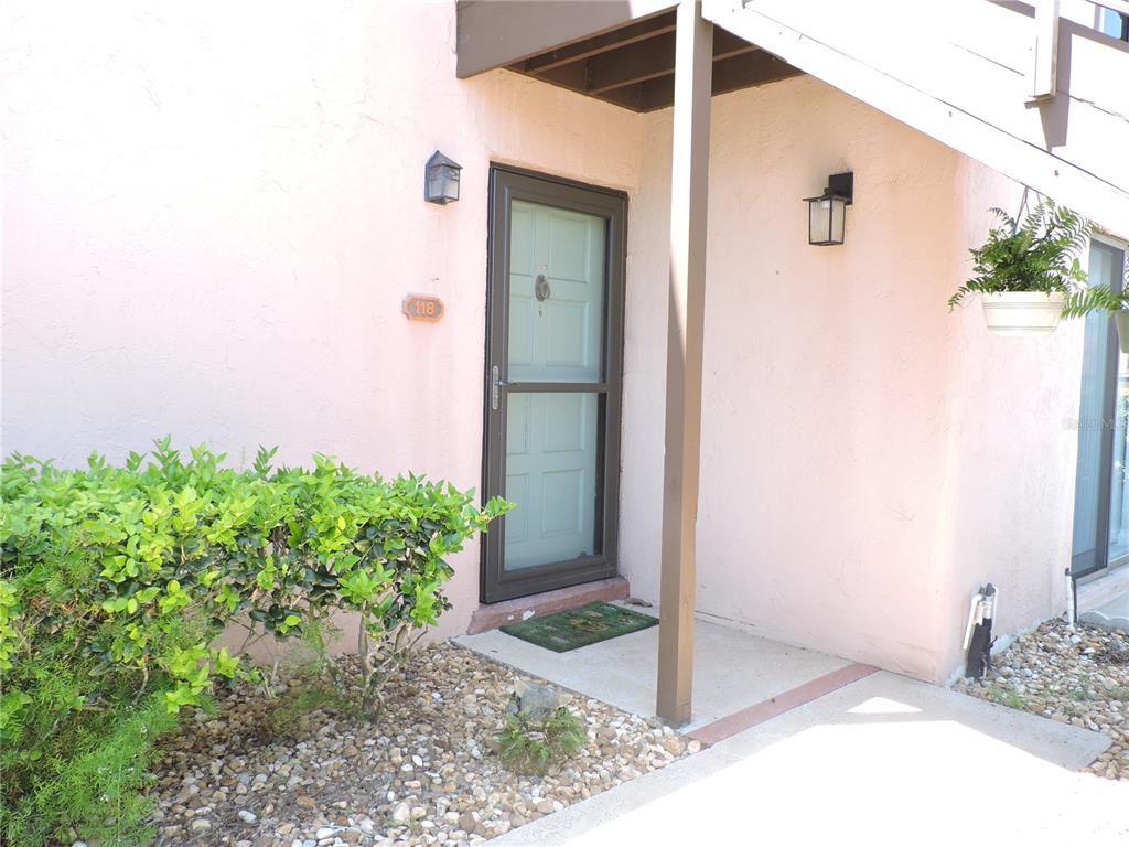 A light pink exterior wall features a front door with a screen door and number 118 — 118 LA CASA UNIT 118, LAKE WALES, FL
