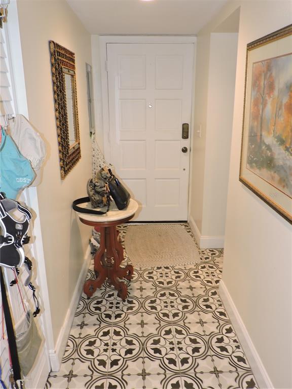 An entryway features patterned tile flooring, a small pedestal table, and a white front door — 118 LA CASA UNIT 118, LAKE WALES, FL