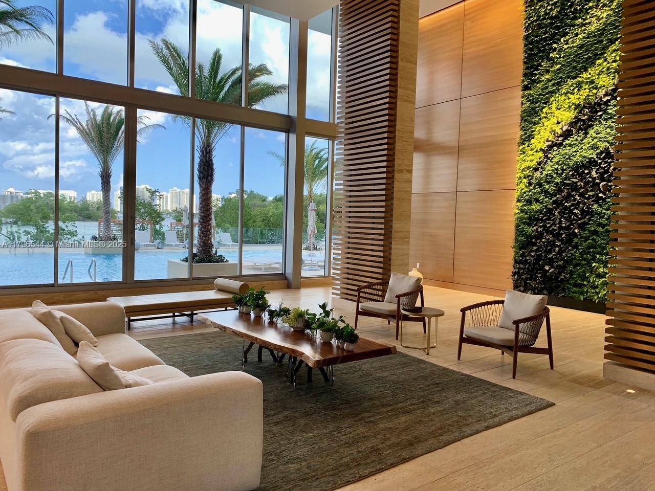 A modern lobby features a living wall, floor-to-ceiling windows, and a view of a pool — 16385 Biscayne Blvd, North Miami Beach FL 33160, NORTH MIAMI BEACH, FL