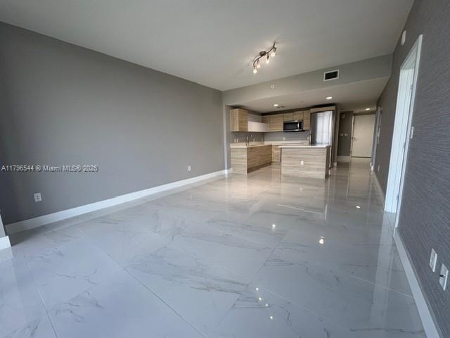 An open-concept kitchen with light wood cabinets and marble-style tile flooring in a living area — 16385 Biscayne Blvd, North Miami Beach FL 33160, NORTH MIAMI BEACH, FL