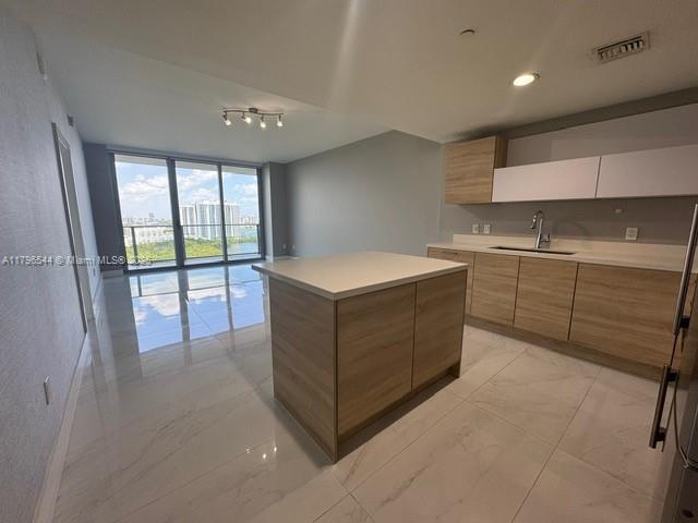 A modern kitchen features light wood cabinets, a central island, and large windows with water views — 16385 Biscayne Blvd, North Miami Beach FL 33160, NORTH MIAMI BEACH, FL