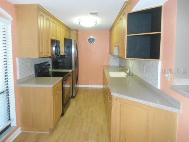 A kitchen features light wood cabinets, light countertops, and stainless steel appliances — 2700 COVE CAY DRIVE UNIT 5D, CLEARWATER, FL