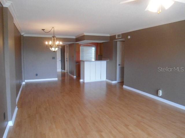 An open-concept living and dining area features light wood-look flooring and dark brown walls — 2700 COVE CAY DRIVE UNIT 5D, CLEARWATER, FL