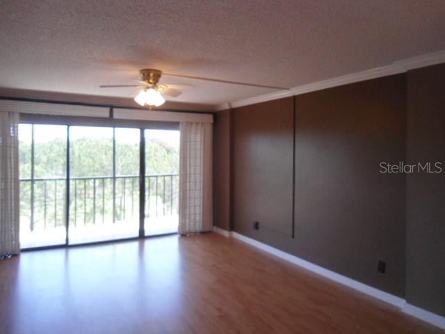 An empty room with wood-look flooring, a ceiling fan, and sliding glass doors to a balcony — 2700 COVE CAY DRIVE UNIT 5D, CLEARWATER, FL