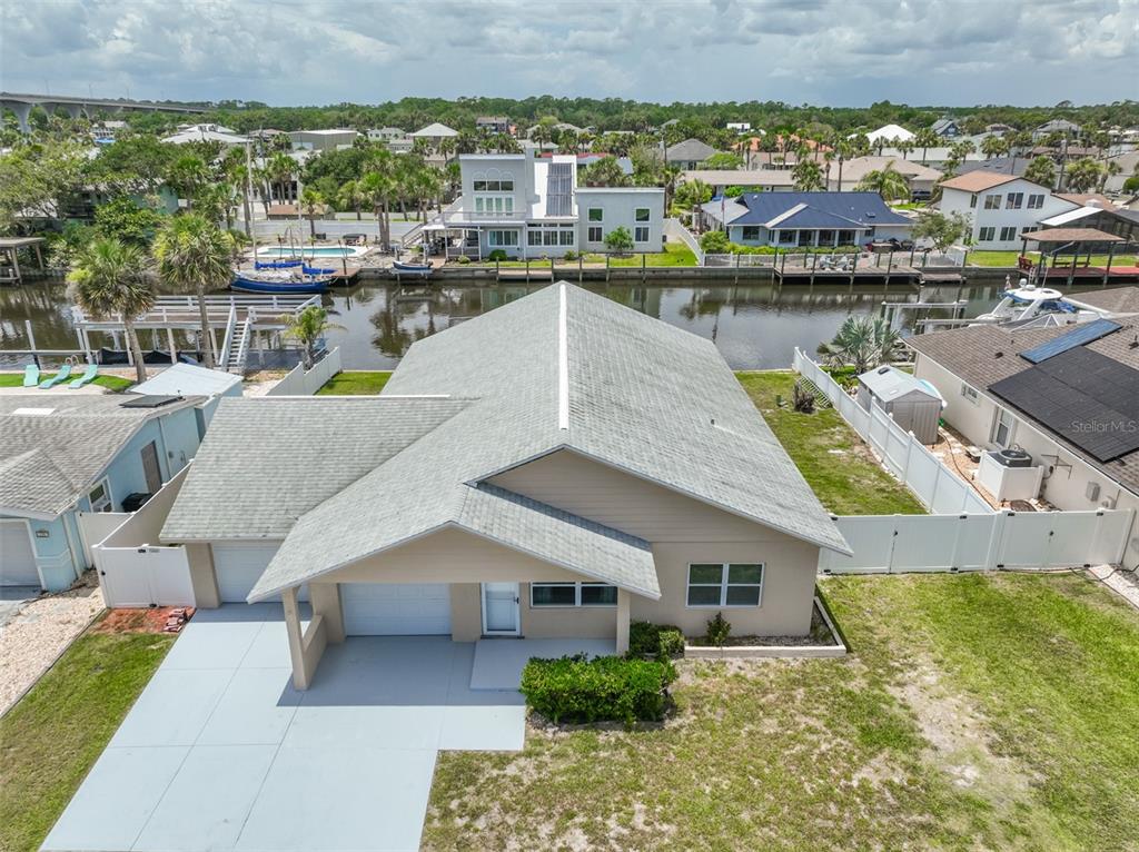 An aerial view of a single-story house with a gray roof and a canal backyard — 143 AVALON AVENUE, FLAGLER BEACH, FL
