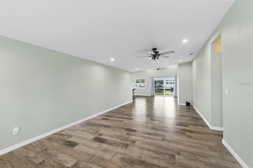 An empty living room with light green walls, wood-look tile flooring, and a ceiling fan — 143 AVALON AVENUE, FLAGLER BEACH, FL