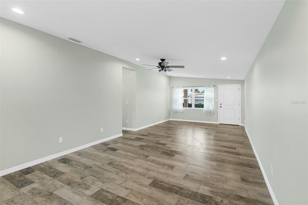 An empty living room features light gray walls, wood-look tile flooring, and a ceiling fan — 143 AVALON AVENUE, FLAGLER BEACH, FL