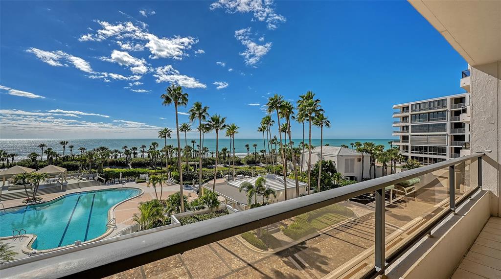 A multi-story residential building with curved balconies stands behind a circular driveway and landscaping — 545 SANCTUARY DRIVE UNIT B305, LONGBOAT KEY, FL