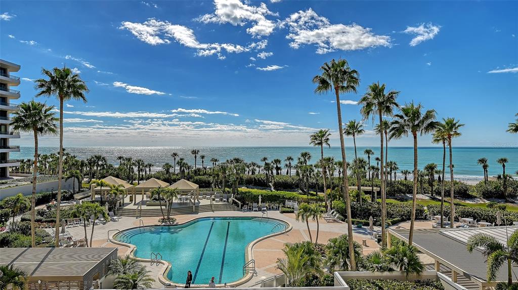 A view of palm trees, a white building, and the ocean under a blue sky — 545 SANCTUARY DRIVE UNIT B305, LONGBOAT KEY, FL