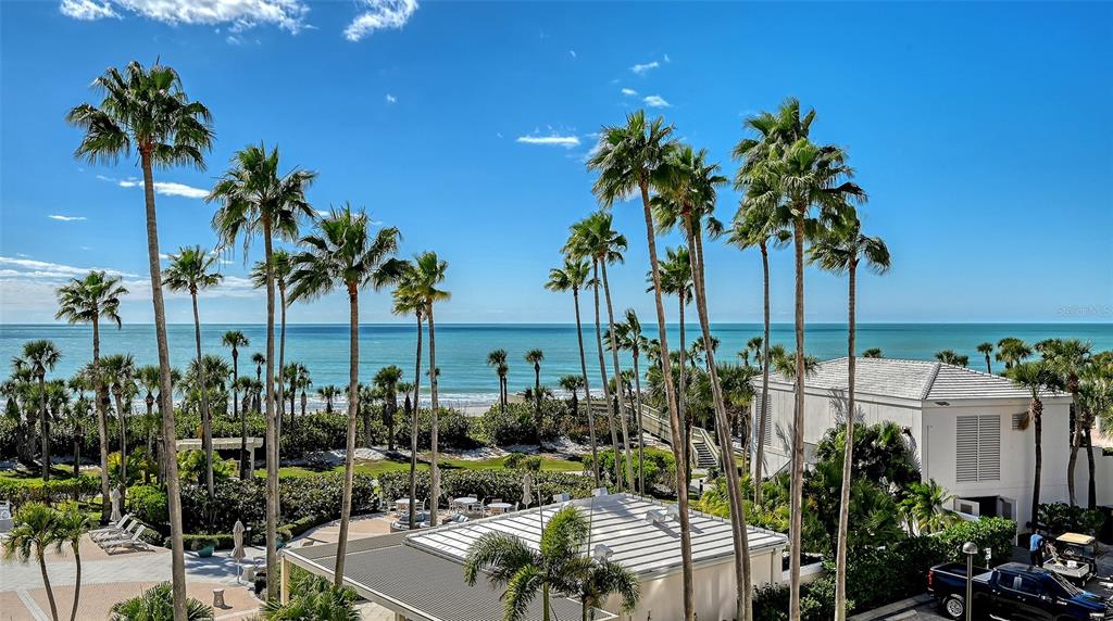 A swimming pool and palm trees overlook the ocean during a vibrant sunset — 545 SANCTUARY DRIVE UNIT B305, LONGBOAT KEY, FL