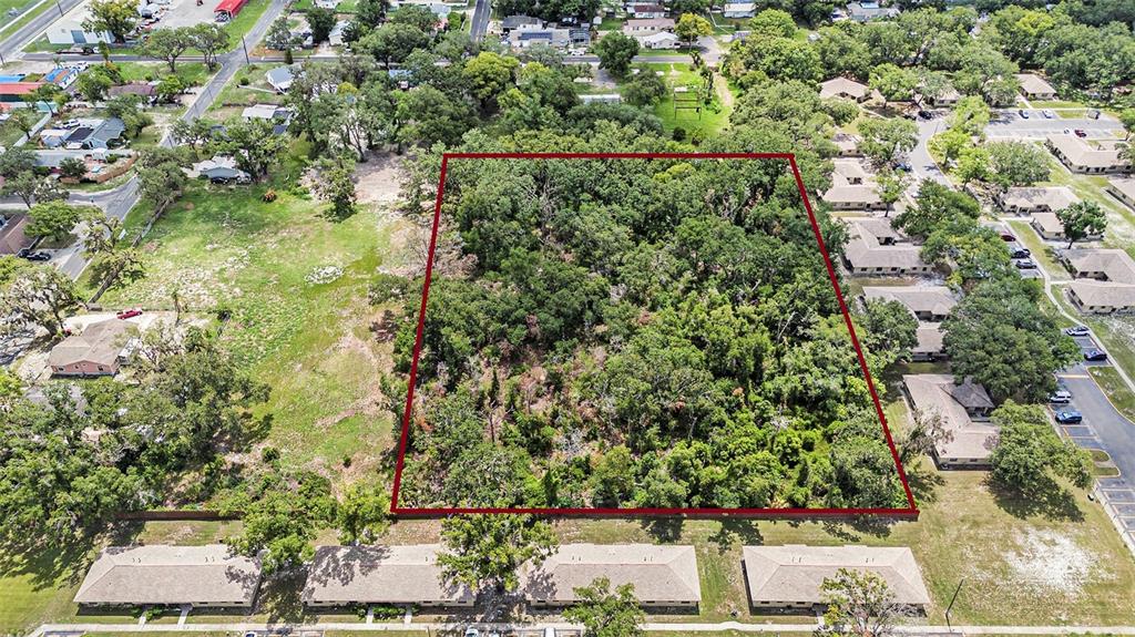 An aerial view shows a rectangular wooded lot outlined in red next to residential buildings — 204513-0000, PLANT CITY, FL