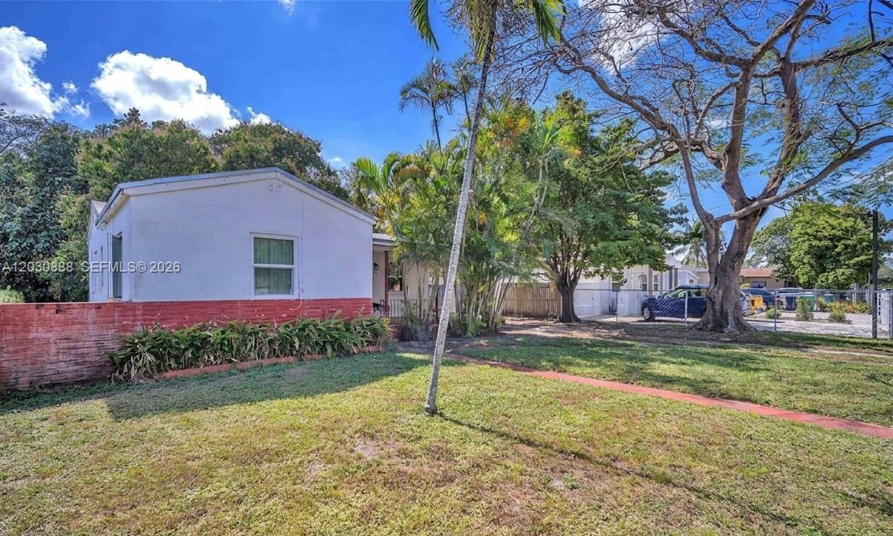 A white house with a red brick base sits on a grassy lot with trees — 1236 Jann Ave, Opa-Locka FL 33054, OPA-LOCKA, FL