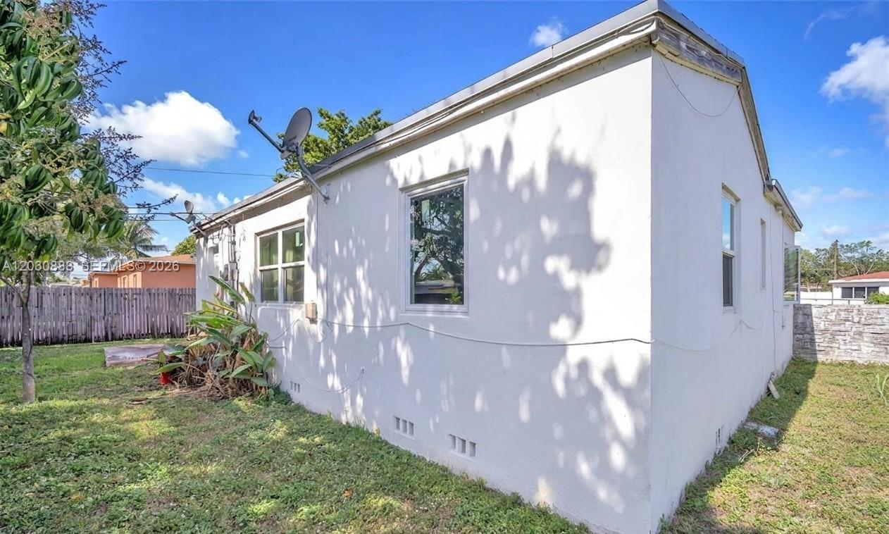 The exterior of a white stucco house features a satellite dish and several windows — 1236 Jann Ave, Opa-Locka FL 33054, OPA-LOCKA, FL