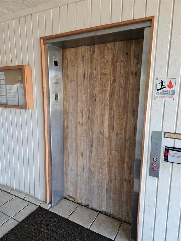An elevator with a wood-look door is set into a white paneled wall — 5981 Via Vermilya # 203, Lake Worth FL 33462, LAKE WORTH, FL