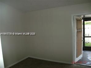 An empty room with beige walls, carpeted flooring, and a door leading to a screened patio — 1338 White Pine Dr, Wellington FL 33414, WELLINGTON, FL
