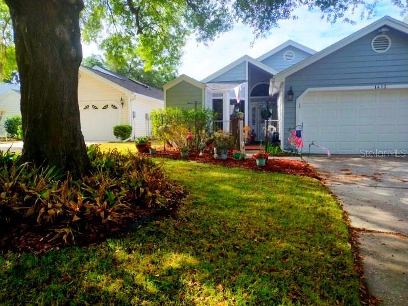 A light blue house with a white garage and a large tree in the front yard — 1412 WALDEN OAKS PLACE, PLANT CITY, FL