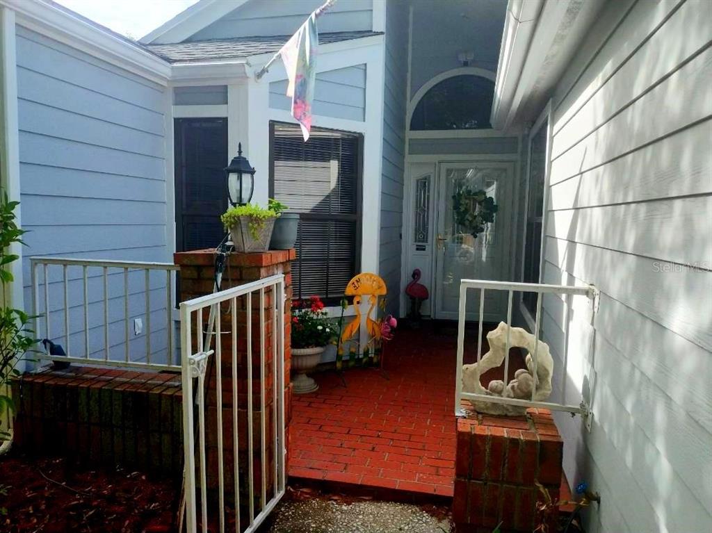 A brick walkway leads to the front entrance of a house with light blue siding — 1412 WALDEN OAKS PLACE, PLANT CITY, FL