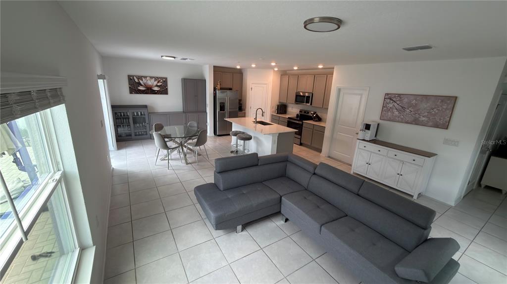 An open-concept kitchen and living area features a gray sectional sofa, dining table, and island — 637 BELL PRAIRIE CIRCLE, LAKE WALES, FL