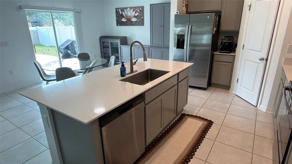 A kitchen island with a sink and dishwasher sits in front of a dining area — 637 BELL PRAIRIE CIRCLE, LAKE WALES, FL