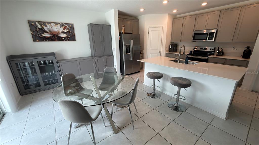 A kitchen and dining area feature gray cabinetry, a glass table, and a white island — 637 BELL PRAIRIE CIRCLE, LAKE WALES, FL