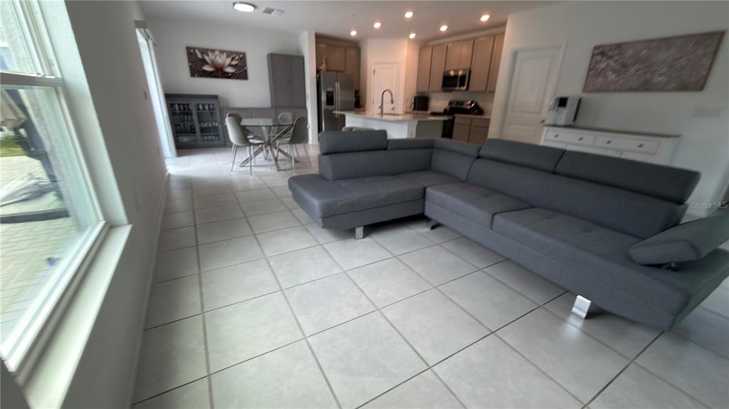 A gray sectional sofa sits on a tiled floor in an open-concept living and kitchen area — 637 BELL PRAIRIE CIRCLE, LAKE WALES, FL