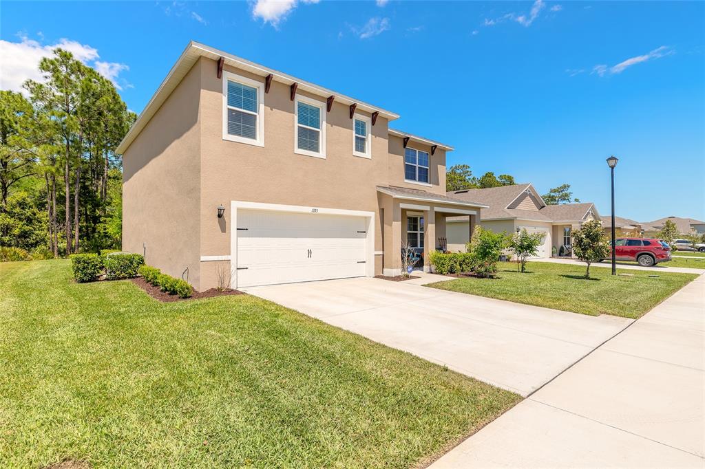 A two-story tan stucco house with a two-car garage and a concrete driveway — 1333 MORNING WALK DRIVE, ORMOND BEACH, FL