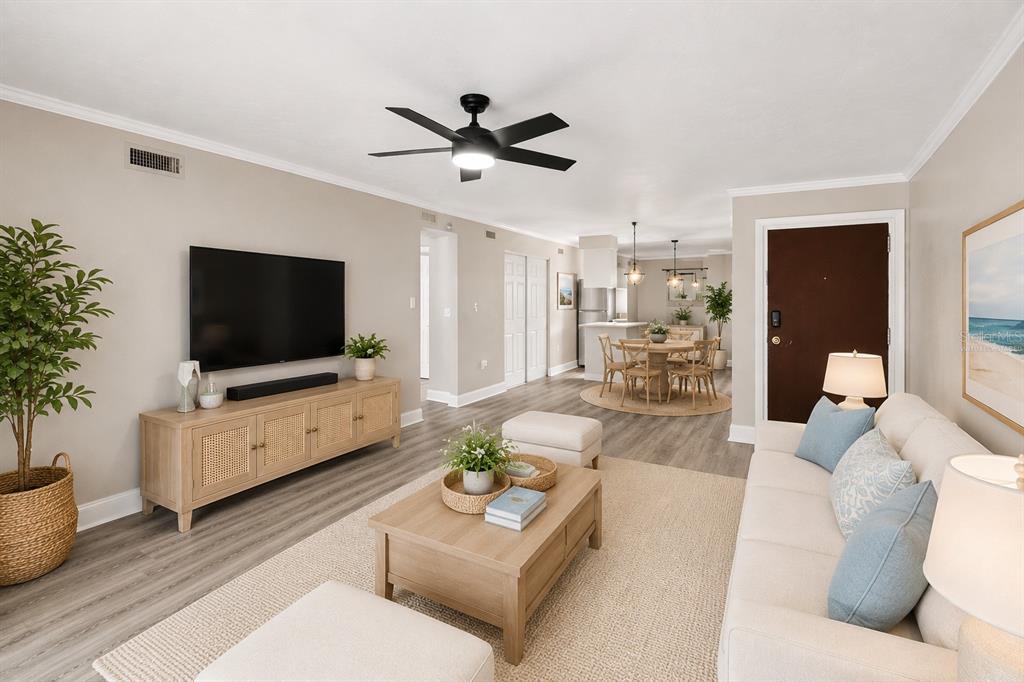 A living room with light wood flooring, a beige sofa, and a dining area beyond — 2717 HIDDEN LAKE BOULEVARD UNIT B, SARASOTA, FL